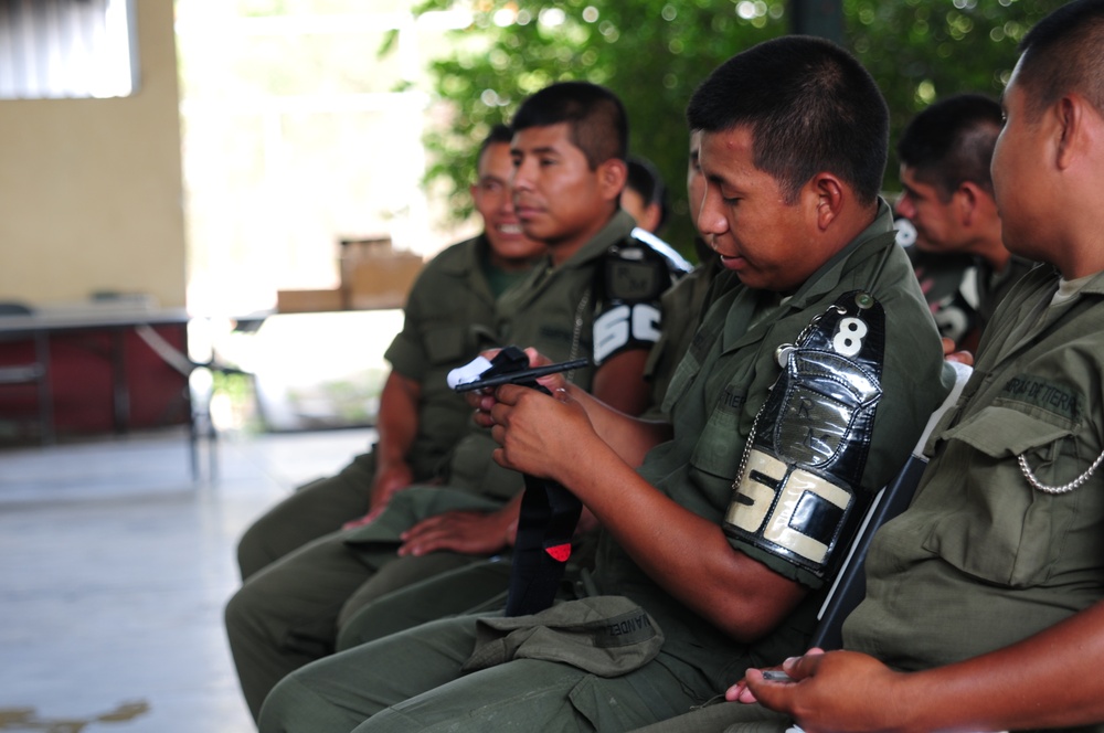 A Guatemalan soldier examines a combat application tourniquet during a Combat Life Savers (CLS) course