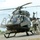 A military medical evacuation (MEDEVAC) helicopter, identifiable by the red cross markings, is on the ground at what appears to be a forward operating base or military airfield. Several soldiers in U.S. Army combat uniforms are gathered around the aircraft, with a pilot visible in the cockpit. The scene suggests a pre-flight briefing, post-landing debrief, or training exercise.