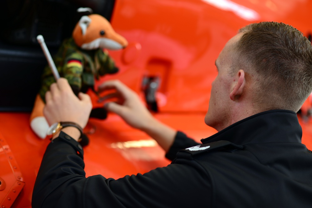 A NATO officer places his air crew's mascot on a Coast Guard helicopter