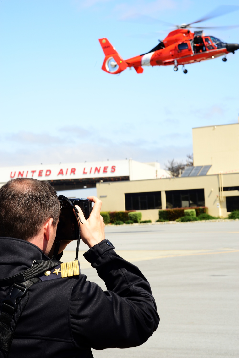 A NATO officer takes a photo of a helicopter demonstration at Coast Guard Air Station San Francisco
