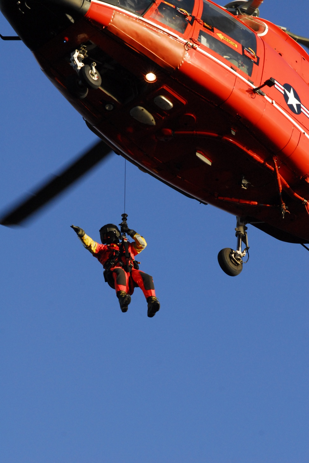 Coast Guard MH-65 Dolphin helicopter crew conducts vertical surface training hoist operation in Kodiak, Alaska