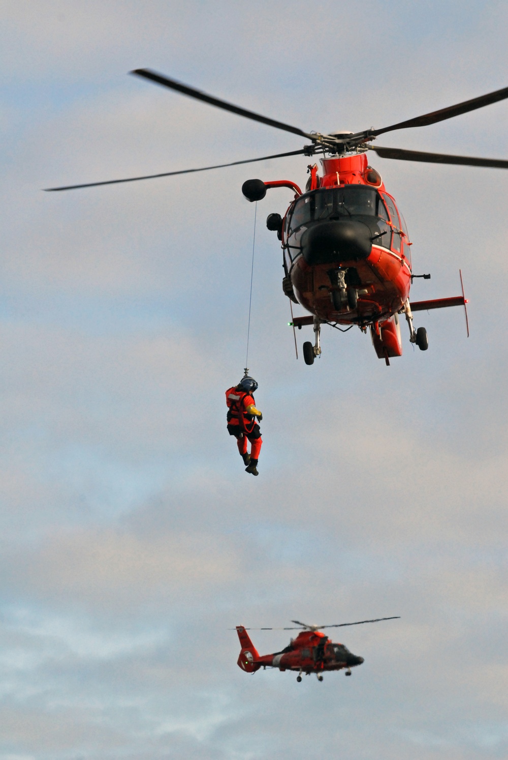 Coast Guard MH-65 Dolphin helicopter crew conducts vertical surface training hoist operation in Kodiak, Alaska