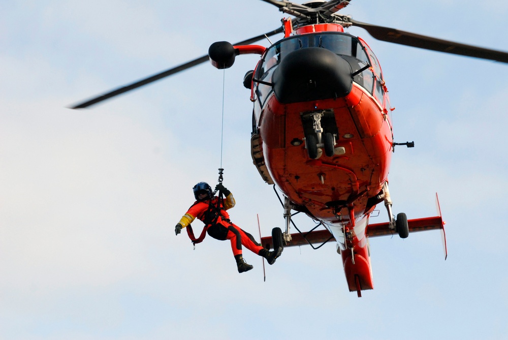 Coast Guard MH-65 Dolphin helicopter crew conducts vertical surface training hoist operation in Kodiak, Alaska