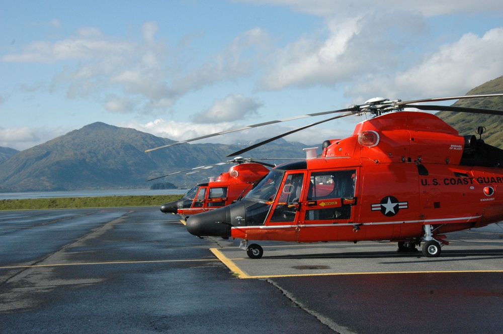 Coast Guard MH-65 Dolphin helicopters stand ready for deployment on the flight line in Kodiak, Alaska