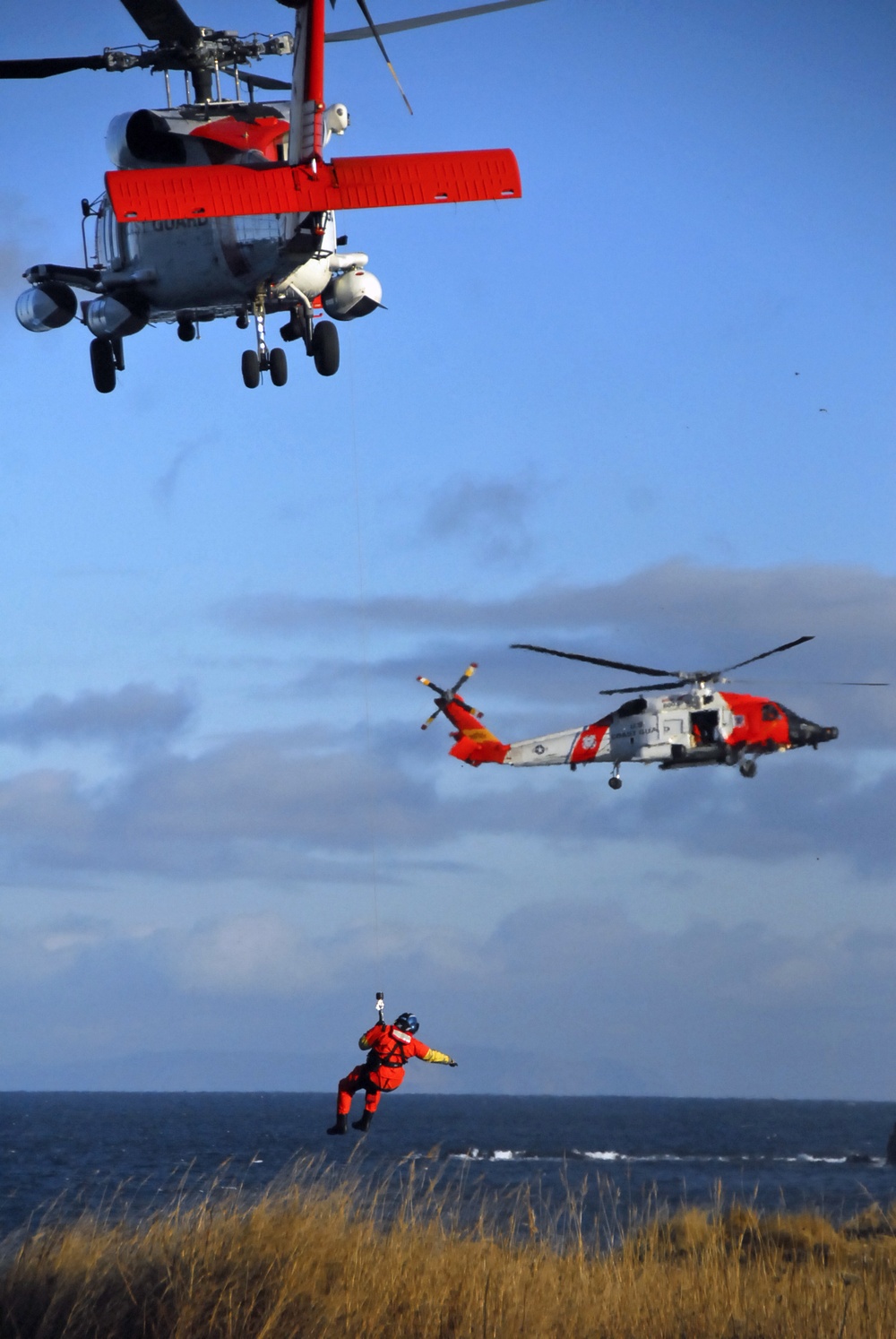 Coast Guard MH-60 Jayhawk helicopter crew conducts vertical surface training hoist operation in Kodiak, Alaska