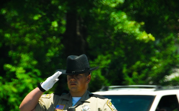 A Stafford County, Virginia, deputy sheriff temporarily closing a roadway, salutes the funeral procession