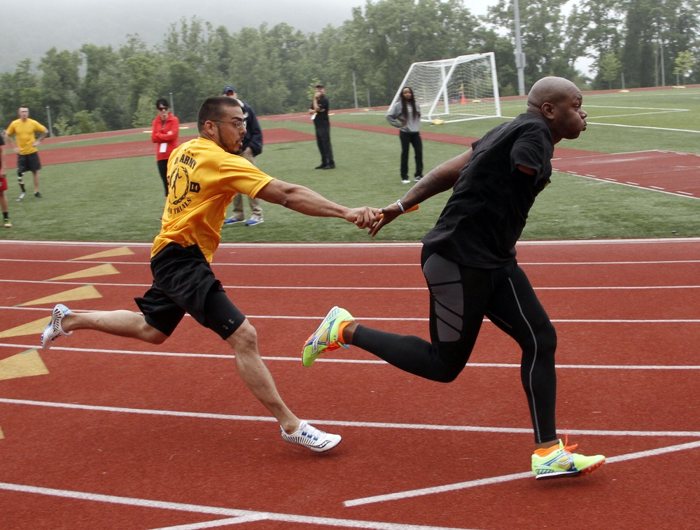 Two Army track team members smoothly pass the baton during practice at the 2014 Army Warrior Trials