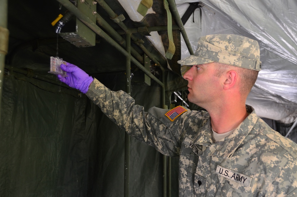 Spc. Sean Walton, preventive medicine specialist from the 787th Medical Detachment, New Orleans, collects water from the showers for testing