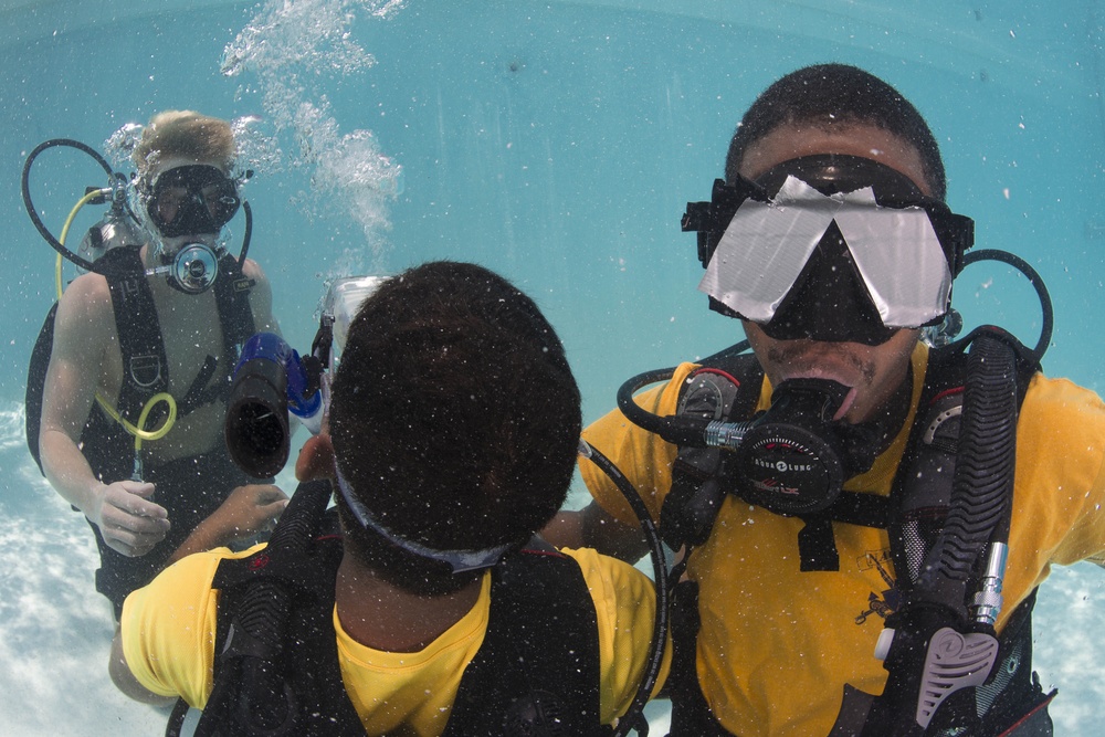 US Navy divers and Belizean coast guard divers practice SCUBA emergency procedures in a pool