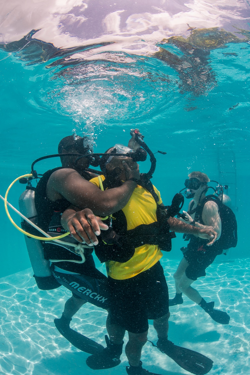 US Navy divers and Belizean coast guard divers practice SCUBA emergency procedures in a pool