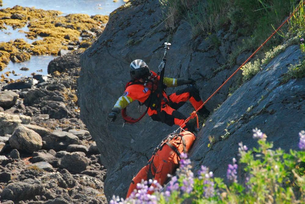 Coast Guard MH-65 Dolphin helicopter crew conducts vertical surface training hoist operation in Kodiak, Alaska