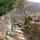 A dated photograph from July 14, 2008 showing a fortified defensive position in a mountainous, arid terrain. The position features green sandbag emplacements arranged between large boulders and a dry-stone wall, suggesting a military or paramilitary checkpoint or fighting position. The background reveals terraced hillsides and vegetation-covered mountains consistent with South Asian or Middle Eastern highland geography.