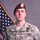 A U.S. Army soldier poses for an official military portrait in Army Combat Uniform (ACU) against a gray studio backdrop with an American flag visible to the left. The soldier wears a maroon beret with a flash insignia and displays multiple qualification badges on his uniform. His name tape reads 'PITTS' and his rank insignia indicates Staff Sergeant.