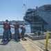Sailors assigned to the aircraft carrier USS Nimitz (CVN 68) handle lines as the Wasp-class amphibious assault ship USS Essex (LHD 2) moors to the pier at Naval Station Everett