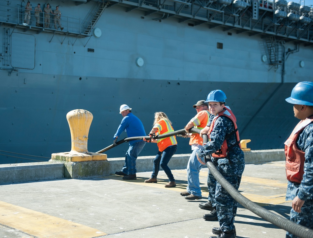 Sailors assigned to the aircraft carrier USS Nimitz (CVN 68) and Navy contractors handle lines as the Wasp-class amphibious assault ship USS Essex (LHD 2) departs from Naval Station Everett