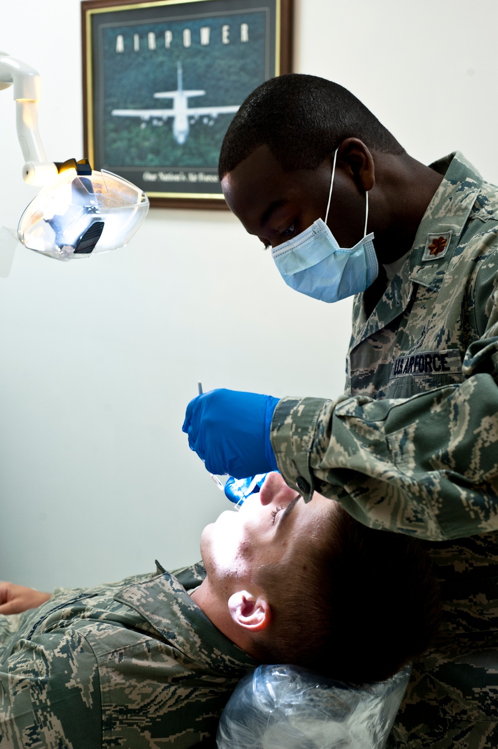 Maj. Stanley Michel conducts a routine dental examination on Senior Airman Eric Mann