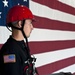 Senior Airman Aaron Breindamour awaits instruction during a confined spaces exercise with the U.S. flag as a backdrop