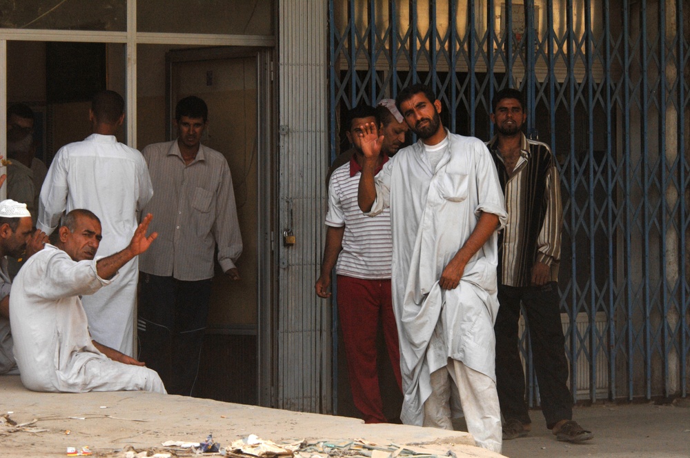 Iraqi shop owners wave to US Army Soldiers