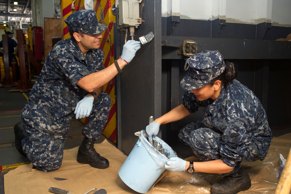 USS George Washington sailors paint in hangar bay