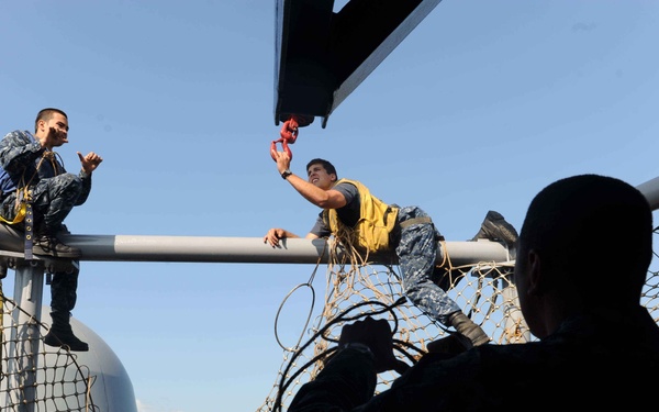 USS John C. Stennis Sailors install a safety net along the flight deck