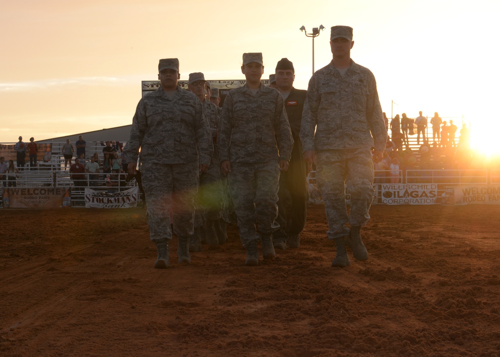 Airmen unfold a US flag at the 36th Annual Great Plains Stampede Rodeo
