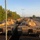 1st Cavalry arrives in Poland A large column of M1 Abrams main battle tanks painted in desert tan/sand camouflage are staged on what appears to be a rail yard or staging area. The tanks bear unit markings consistent with U.S. Army cavalry units, with at least one tank marked 'C22' and '1CAM-2-8CAV' visible. The scene appears to be taken during early morning or late afternoon light, with civilian observers visible in the background.