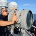 USS Cole Sailor uses signal lamp to communicate with USS Ross