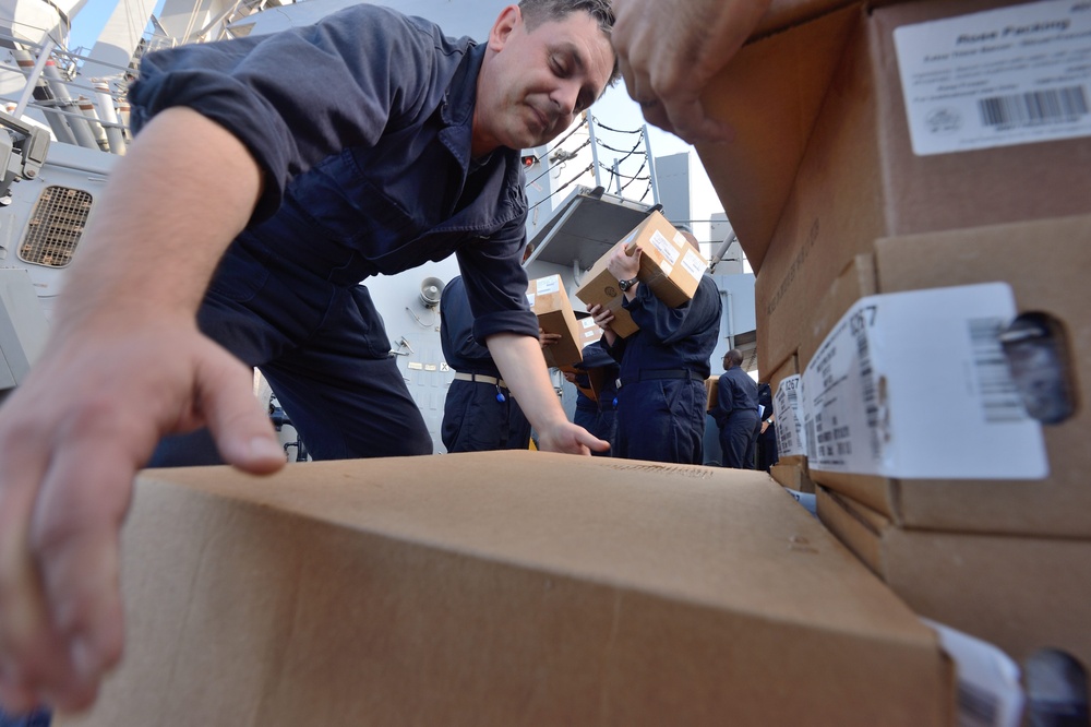 USS Cole sailors move boxes during replenishment