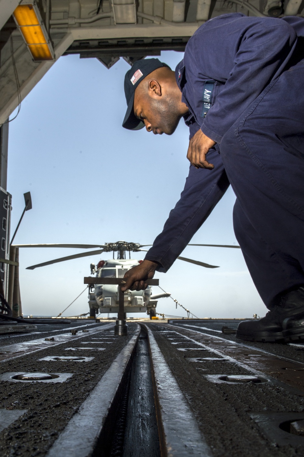 USS Philippine Sea Sailor performs maintenance on a helicopter rapid securing device