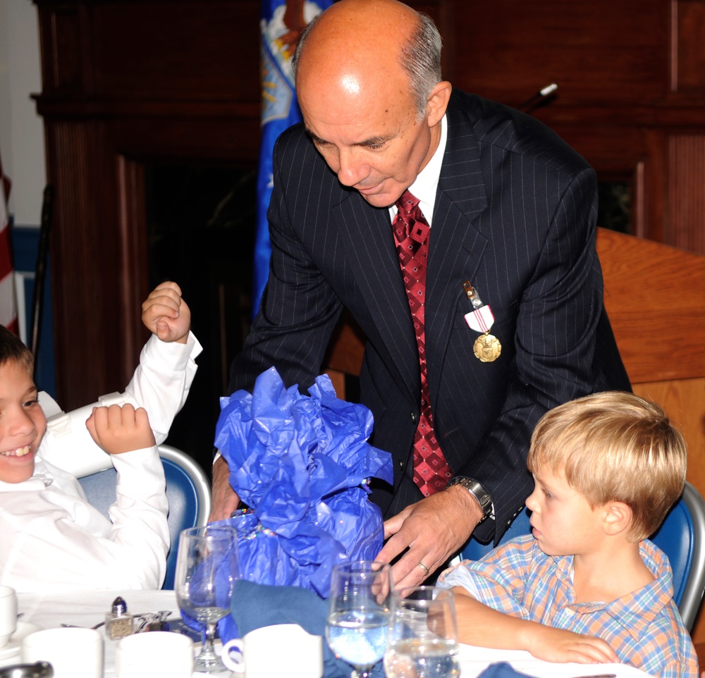 Civilian gives gifts to grandchildren at his retirment ceremony