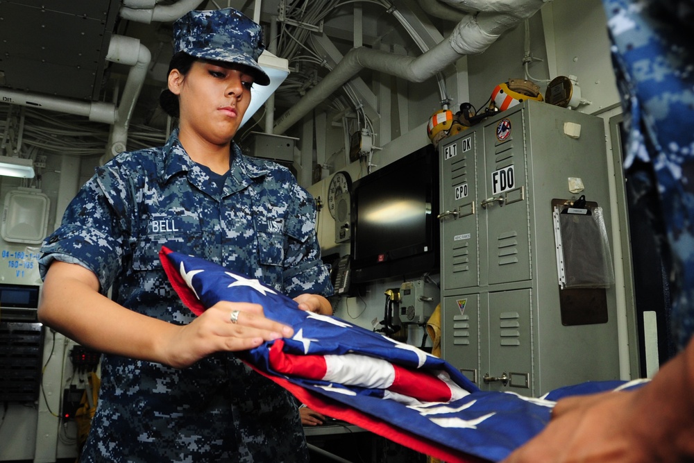 USS George H.W. Bush sailor folds flag