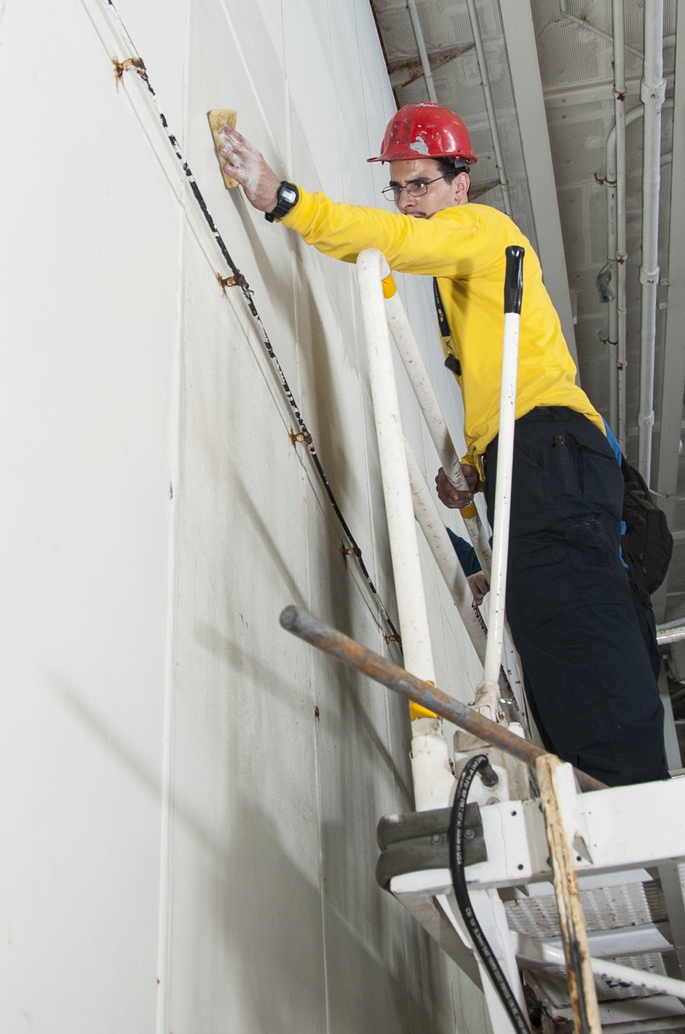 USS George H.W. Bush Sailor cleans a hangar bay door