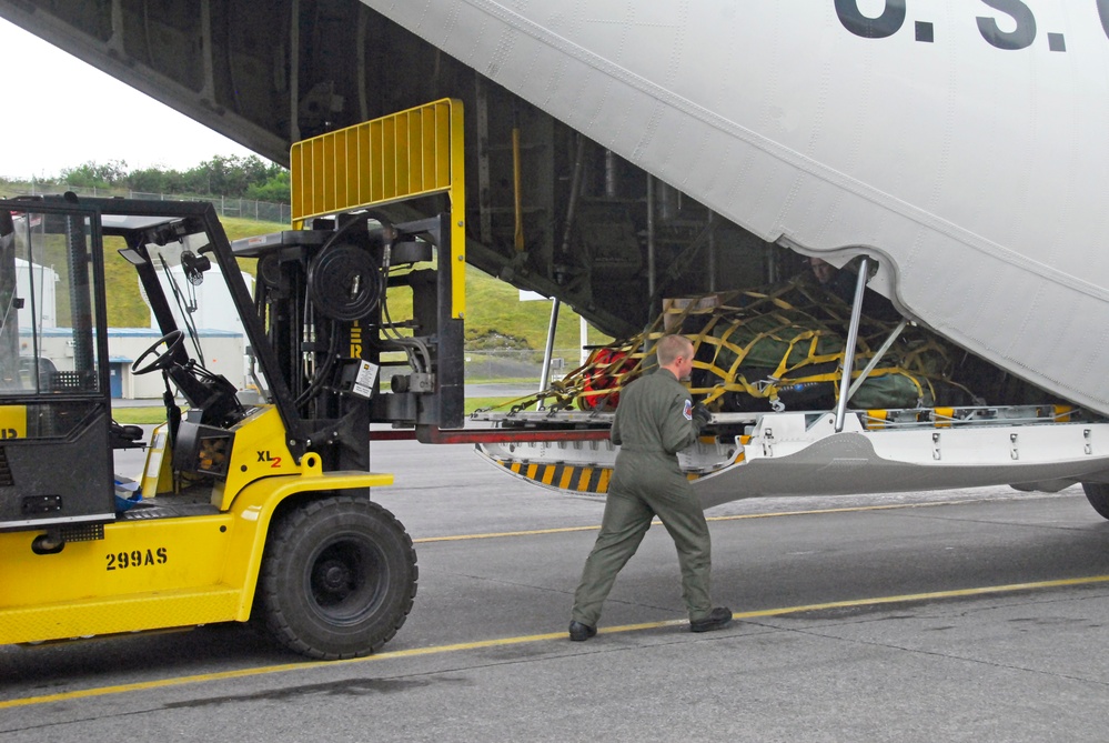 Coast Guard aviation maintenance technician unloads cargo from a HC-130 Hercules aircraft in Kodiak, Alaska