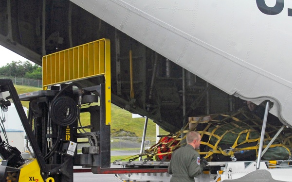 Coast Guard aviation maintenance technician unloads cargo from a HC-130 Hercules aircraft in Kodiak, Alaska
