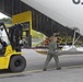Coast Guard aviation maintenance technician unloads cargo from a HC-130 Hercules aircraft in Kodiak, Alaska