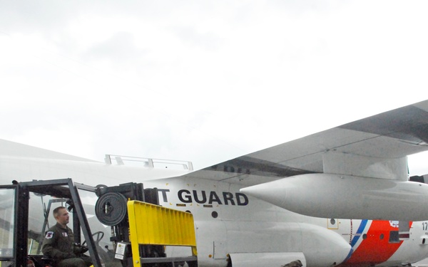 Coast Guard aviation maintenance technician unloads cargo from a HC-130 Hercules aircraft in Kodiak, Alaska
