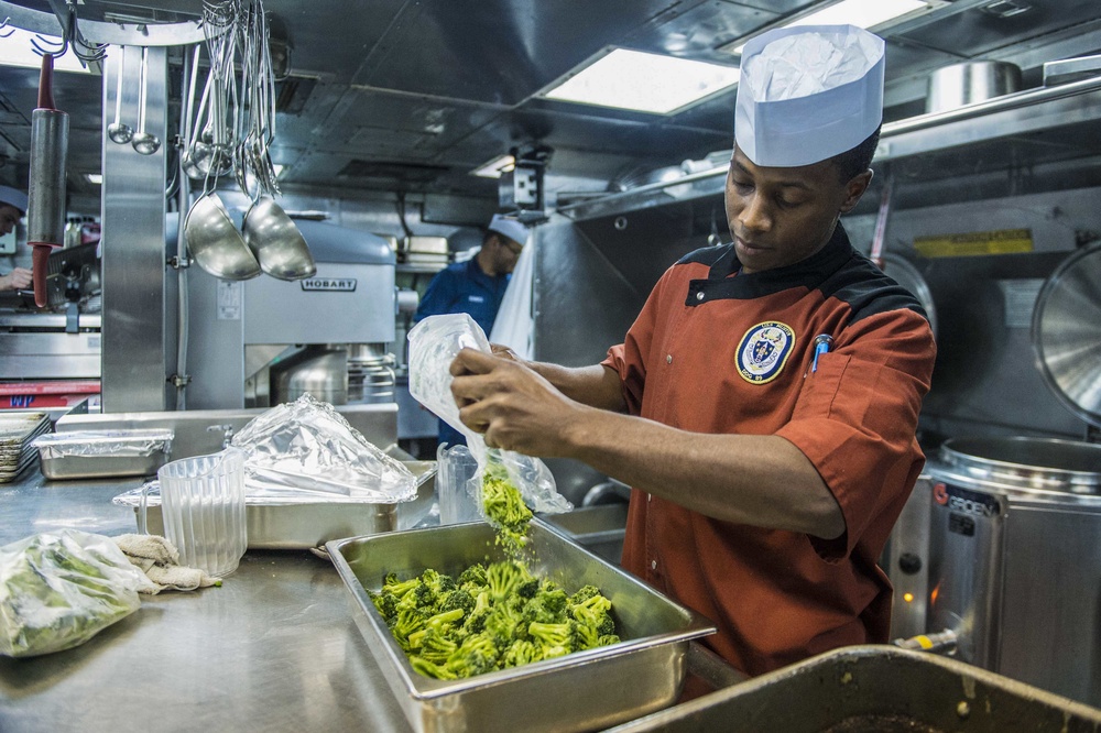 USS Mustin Sailor prepares food
