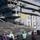 A F-35C Lightning II stealth fighter jet (bureau number 75) is positioned on the flight deck of a U.S. Navy aircraft carrier, identified by the hull number '68' visible on the island superstructure. Ground crew members from VX-23 test squadron are conducting pre-flight or post-flight operations around the aircraft. The pilot, identified on the fuselage as 'Mr. Elliot Hemo Clemence,' is seated in the cockpit.