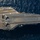 An aerial photograph of a large aircraft carrier at sea, viewed from above and slightly to the side. The flight deck is visible with at least two fixed-wing aircraft positioned on it, along with runway markings, catapult tracks, and deck equipment. The hull number '08' is visible on the bow of the vessel.