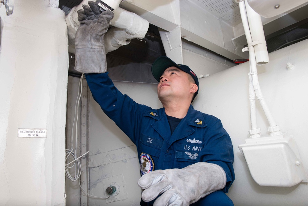 USS John C. Stennis Sailor installs end cap on a pipe