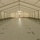 The interior of a large temporary relief tent, likely a humanitarian aid shelter or field hospital. Rows of military-style folding cots are arranged along both sides of a central aisle on a plastic floor covering marked with 'USAID' branding. The structure appears newly set up and currently unoccupied.