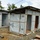 The image shows temporary structures constructed using USAID-branded tarpaulins and wooden framing, with corrugated metal roofing. These appear to be emergency or humanitarian aid facilities, likely an Ebola Treatment Unit (ETU) or similar medical/relief structure based on the construction style and USAID branding. The site appears to be under construction or recently completed, with building materials scattered on the ground.