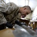 U.S. Marine Gunnery Sgt. Joshua W. Hairston, the Exploitation Analysis Center Lab Chief Special Purpose Marine Air Ground Task Force – Crisis Response – Central Command scrapes paint off exploded ordnance on Dec. 30, 2014.