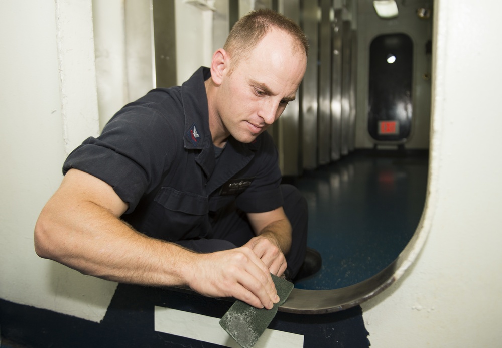 USS Comstock sailor cleans during field day
