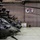 Multiple military helicopters, identifiable as OH-58D Kiowa Warriors, are lined up inside a military hangar. The aircraft are painted in dark olive/black tactical colors and equipped with mast-mounted sights. Two unit insignia patches are displayed on the hangar wall, one reading 'REDCATCHERS' and featuring US and South Korean flag elements, indicating a Korea-based assignment.