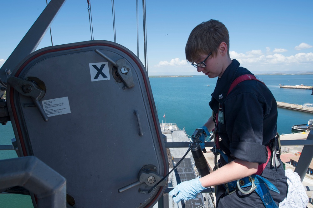 Damage control petty officer performs maintenance on individually dogged doors