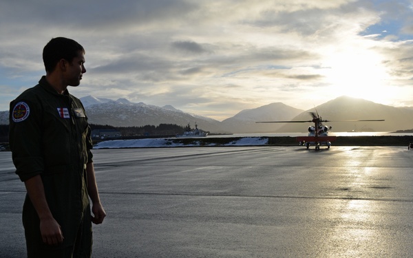 Coast Guard aviation survival technician arrives on the flight line at sunset to stand duty in Kodiak, Alaska