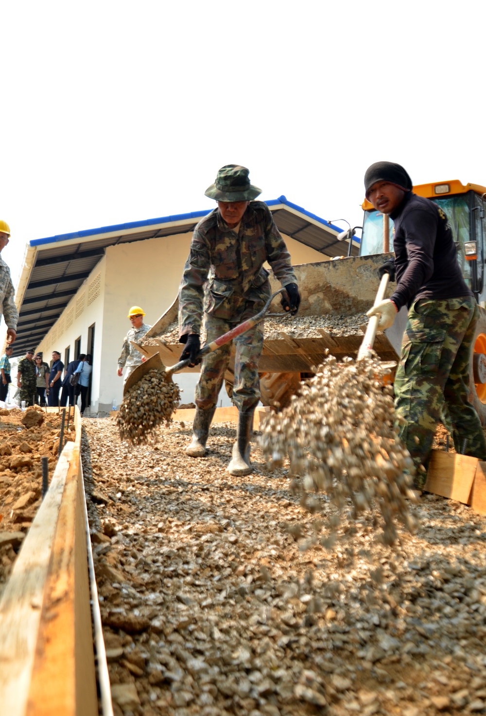 Thai soldiers spread gravel for a sidewalk at a new school