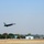 A U.S. Air Force F-16 Fighting Falcon is captured just after takeoff or during a low pass over a runway. The aircraft displays 'WW' tail codes, indicating it belongs to the 35th Fighter Wing based at Misawa Air Base, Japan. The background shows airfield infrastructure including buildings and trees under a hazy sky.