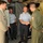 The image shows a group of military personnel inside what appears to be a large military aircraft, likely a cargo or transport plane. Four individuals are present, with two shaking hands in a formal greeting, suggesting an official visit or diplomatic exchange. The personnel are wearing different military uniforms, including a US military flight suit with an American flag patch and what appear to be foreign military dress uniforms.